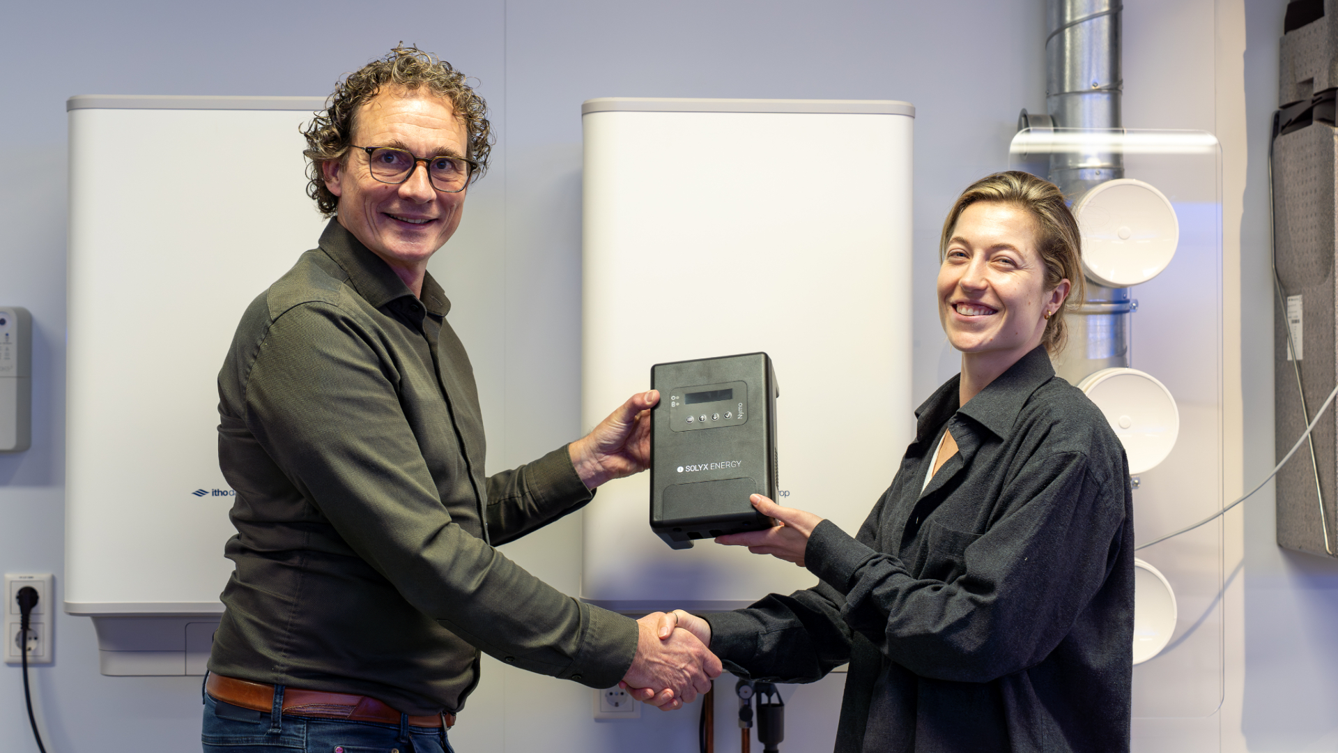 Mark Bussman van Itho Daalderop en Emma Snaak van Solyx Energy schudden elkaar de hand