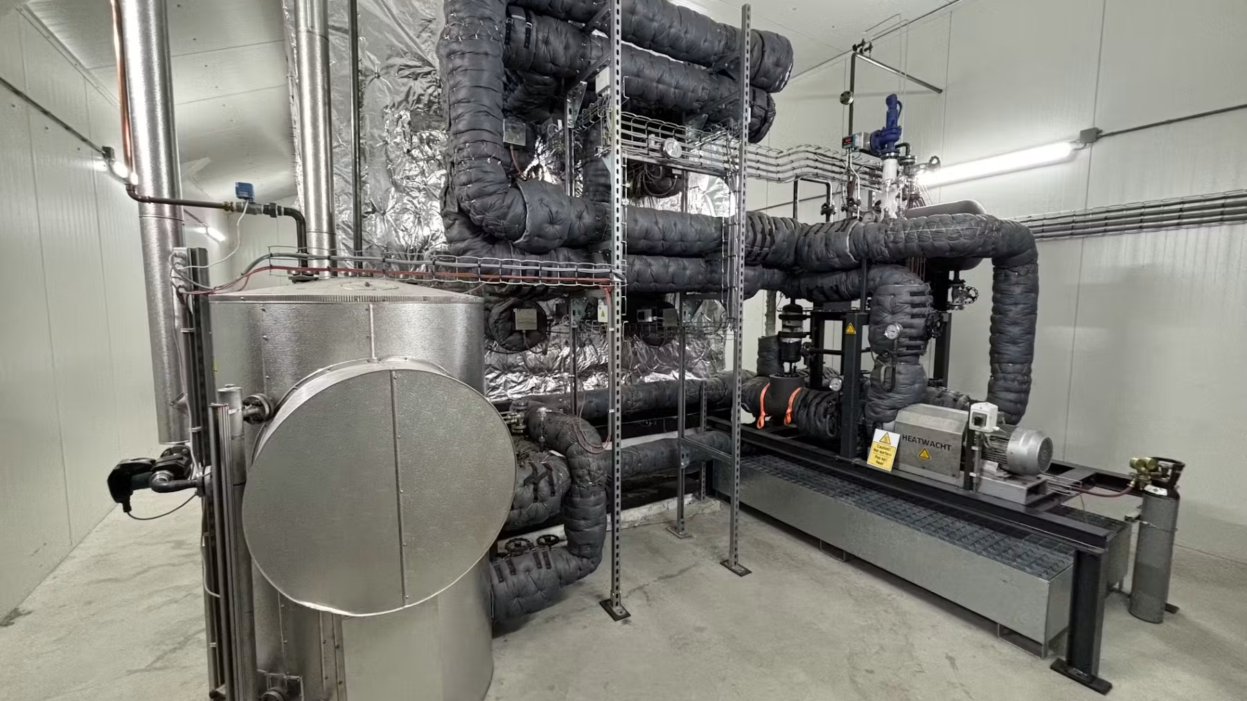 PowerStove-installatie bij Hans Wolters. Het magnetiet zit in de geïsoleerde bak achter de installatie. Het magnetiet in de bak wordt opgewarmd door de warmtewisselaars. Op deze foto staan vier wisselaars. De configuratie bij Nij Smellinghe heeft per module 42 wisselaars. Foto: Heatwacht 